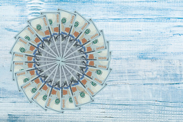 Artistic pattern made from dollar bills Snowflake, flower or star on wooden table. Top view.