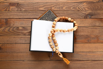 Muslim beads and Koran on wooden background