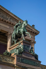 An equestrian statue of Frederick William IV in front of the Alte Nationalgalerie (Old National Gallery) on Museum Island in Berlin, Germany, on a sunny day.