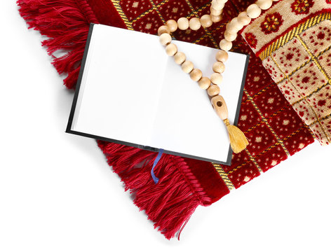 Muslim prayer mat, beads and Koran on white background