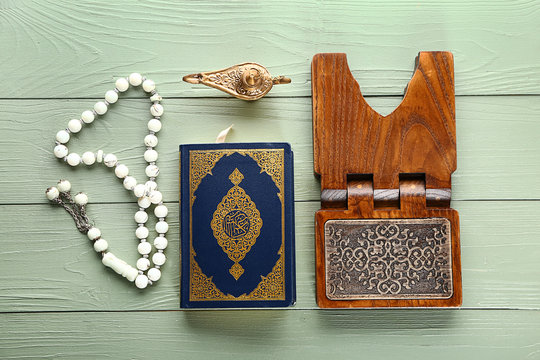 Koran, rehal, Muslim beads and lamp on wooden background