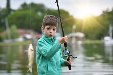 kid boy hold a fish on fishing rod