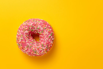 pink donut on yellow background top view copy space