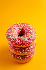 three pink donuts on yellow background top view copy space