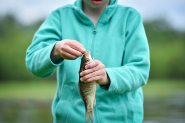 kid boy taking out a hook from the fish