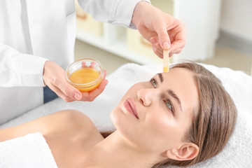 Obraz na płótnie Canvas Young woman undergoing eyebrows epilation in beauty salon