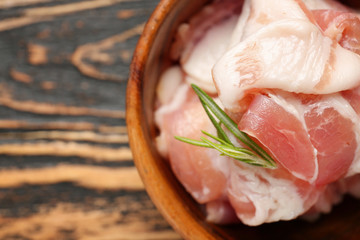 Fresh raw bacon in bowl on wooden background, closeup