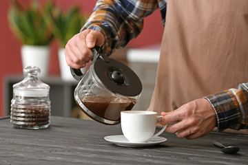 Man pouring coffee in cup at home, closeup