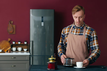Portrait of handsome man pouring coffee in cup at home