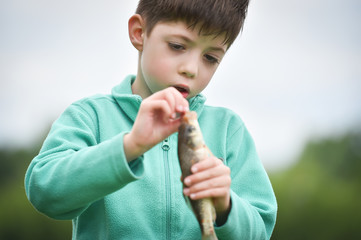 kid boy taking out a hook from the fish
