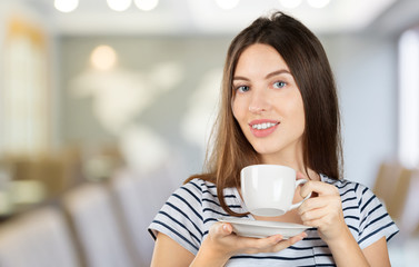 Happy woman enjoying a warm cup of tea or coffee for breakfast