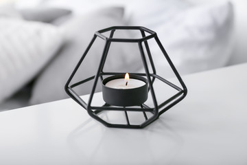 Beautiful burning candle on table in bedroom