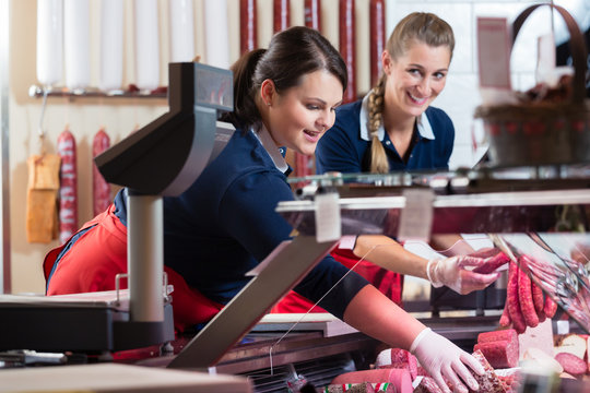 Two sales ladies in butcher shop stuffing the meat display