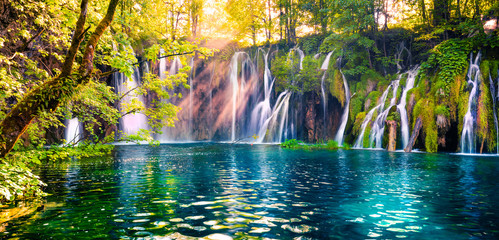 Last sunlight lights up the pure water waterfall on Plitvice National Park. Colorful spring...