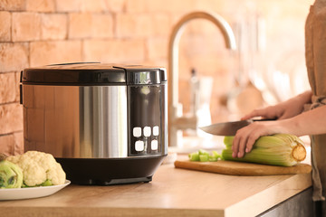 Woman using modern multi cooker in kitchen