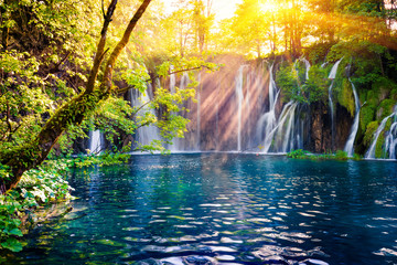 Last sunlight lights up the pure water waterfall on Plitvice National Park. Colorful spring scene of green forest with blue lake. Great countryside view of Croatia, Europe. 
