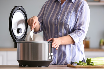 Woman using modern multi cooker in kitchen
