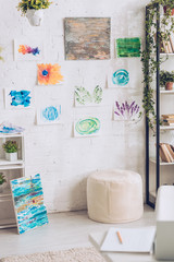 light room with green potted plants and colorful painting on white wall
