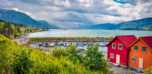 Fototapeta na wymiar Picturesque summer view of typical Norwegian village on the shore of fjord. Traveling concept background.Artistic style post processed photo.