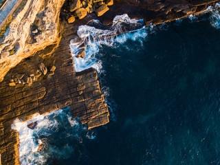 Top down aerial view of rocky coastline under the sunlight.