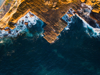 Top down aerial view of rocky coastline under the sunlight.