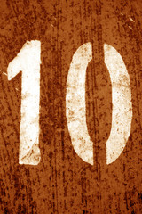 Number 10 in stencil on metal wall in orange tone.