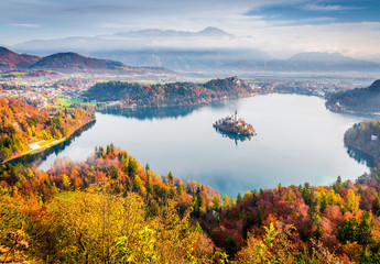 Impressive view of church of Assumption of Maria on the Bled lake. Foggy autumn landscape in Julian Alps, Slovenia, Europe. Beauty of countryside concept background.