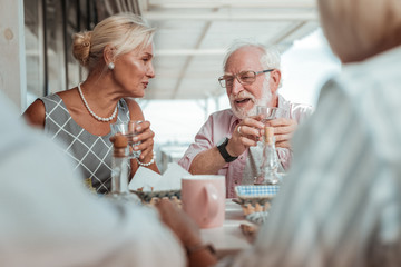 Cheerful elderly couple having dinner with their friends