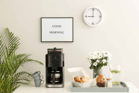 Modern Coffee Machine, Sweets And Flowers On Kitchen Table