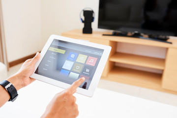 Close-up of woman controlling her TV with online application on digital tablet at home