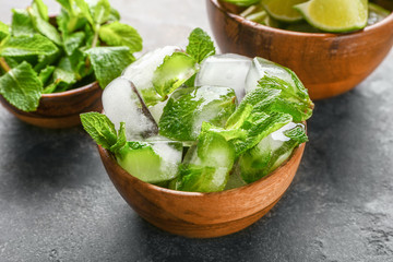 Bowls with fresh mint leaves, lime and ice cubes on grey table