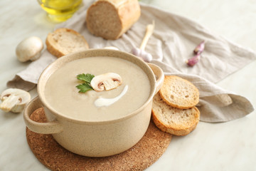 Pot of tasty mushroom cream soup on table