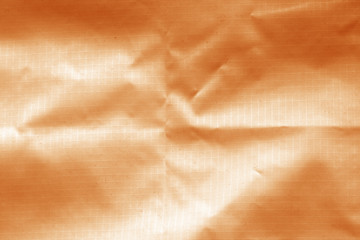 Crumpled transparent plastic surface in orange color.