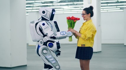 A droid gives red tulips to a girl and she hugs it.