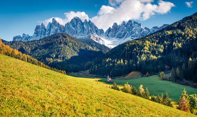 Fototapeta premium Marvelous view of Chiesetta di San Giovanni in Ranui church in front of the Geisler or Odle Dolomites Group. Colorful autumn sunset in Dolomite Alps, Italy, Europe. Traveling concept background.