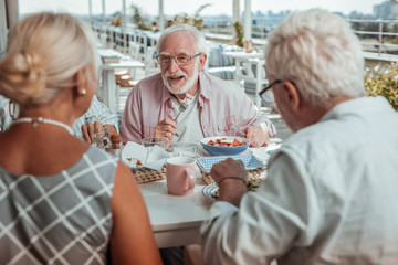 Cheerful bearded man having healthy diner in cafe
