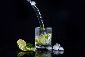 Summer cocktail mojito with splash on black background..