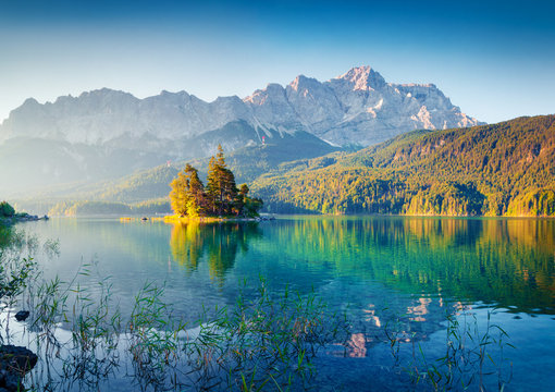 Great summer sunrise on Eibsee lake with Zugspitze mountain range. Sunny outdoor scene in German Alps, Bavaria, Germany, Europe. Beauty of nature concept background.