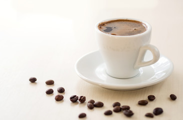 Breakfast. Cup of coffee  and coffee beans on white table