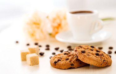 Romantic background. Breakfast. Cookies with chocolate on the background of cups of coffee and flowers.