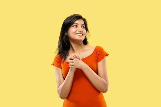 Beautiful female half-length portrait isolated on yellow studio background. Young emotional indian woman in dress astonished and happy. Negative space. Facial expression, human emotions concept.
