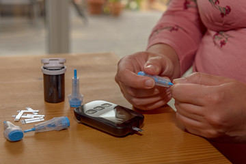 A young woman at home checks her blood sugar. For this she prepares the disposable diabetic lancet device. Concept: health care, people and medicine