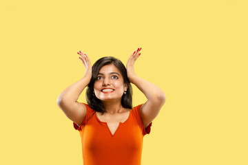 Naklejka premium Beautiful female half-length portrait isolated on yellow studio background. Young emotional indian woman in dress astonished and happy. Negative space. Facial expression, human emotions concept.