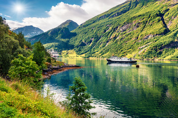 Fototapeta premium Sunny summer scene of Geiranger port, western Norway. Marvelous view of Sunnylvsfjorden fjord. Traveling concept background. Artistic style post processed photo.