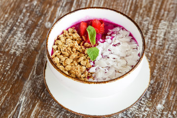 Dragon fruit smoothie bowl with granola and sliced almonds, healthy delicious breakfast option