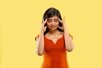 Beautiful female half-length portrait isolated on yellow studio background. Young emotional indian woman in dress thinkful or suffering from the pain. Facial expression, human emotions concept.