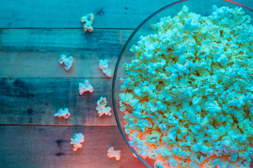 a plate of popcorn on a wooden texture. concept of film viewing, weekend rest, with space, creative light
