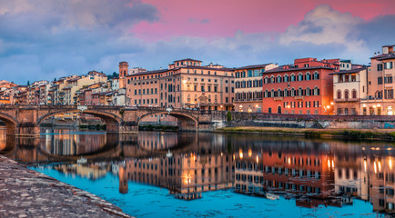 Spectacular medieval arched St Trinity bridge (Ponte Santa Trinita) over Arno river. Colorful spring sunset in Florence, Italy, Europe. Traveling concept background.