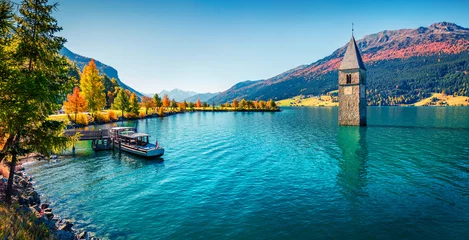 Selbstklebende Fototapeten Grün Blau Panoramablick im Herbst auf den Turm der versunkenen Kirche im Reschensee. Sonnige Morgenszene der italienischen Alpen, Südtirol, Italien, Europa. Reisen Konzept Hintergrund.  © Andrew Mayovskyy