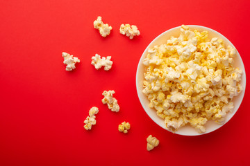 plate with popcorn on a red bright background. movie viewing concept, weekend getaway, with space
